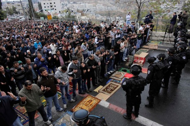 Israeli security forces stand guard as Palestinian Muslim worshippers perform traditional Friday prayers on a street
